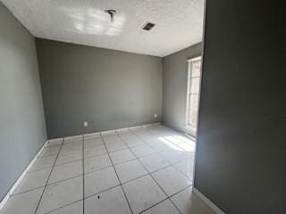 unfurnished room with light tile patterned floors, visible vents, and a textured ceiling