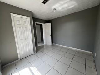 unfurnished bedroom with a closet, visible vents, baseboards, and light tile patterned floors