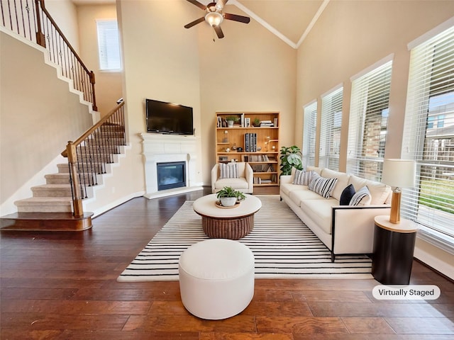 living room with high vaulted ceiling, ornamental molding, stairway, hardwood / wood-style floors, and a glass covered fireplace