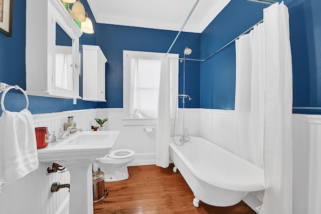 full bathroom with curtained shower, a freestanding bath, toilet, wainscoting, and wood finished floors