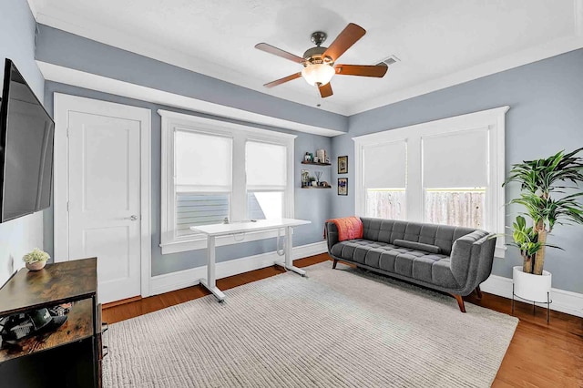 living area with ceiling fan, wood finished floors, visible vents, and baseboards