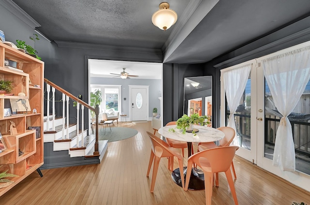 dining area with a textured ceiling, french doors, ornamental molding, stairway, and hardwood / wood-style floors