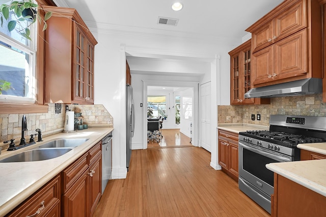 kitchen featuring under cabinet range hood, a sink, visible vents, appliances with stainless steel finishes, and crown molding