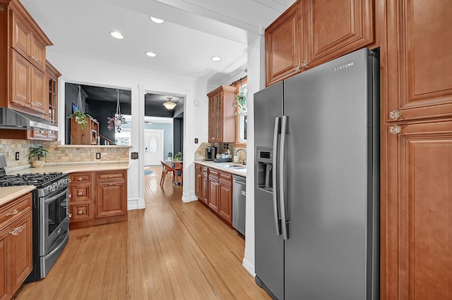 kitchen featuring brown cabinets, light countertops, appliances with stainless steel finishes, light wood-style floors, and a sink