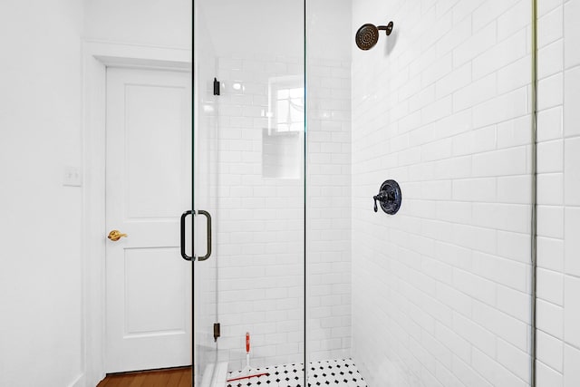 full bath featuring a stall shower and wood finished floors