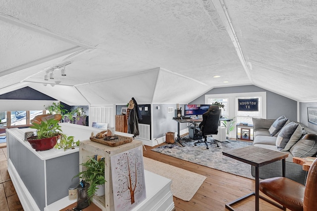 interior space featuring wood-type flooring, vaulted ceiling, and a textured ceiling