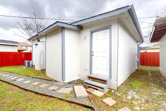 view of outdoor structure with cooling unit, entry steps, and fence