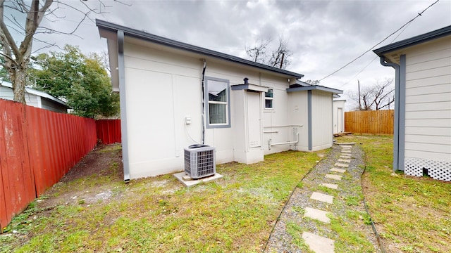 rear view of property featuring a lawn, cooling unit, and a fenced backyard