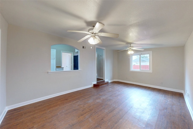 unfurnished room with visible vents, baseboards, a textured ceiling, and dark wood finished floors