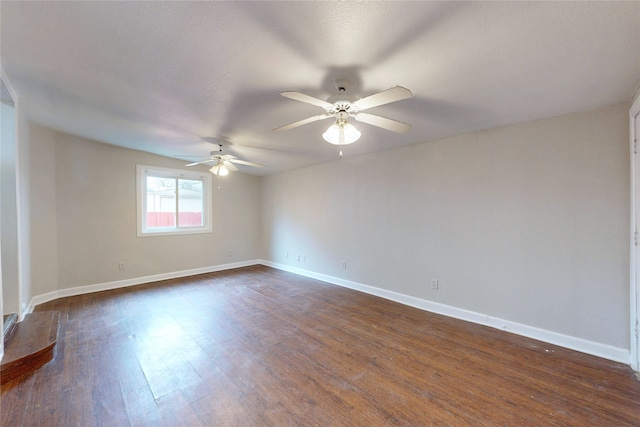 empty room featuring dark wood finished floors, a ceiling fan, and baseboards