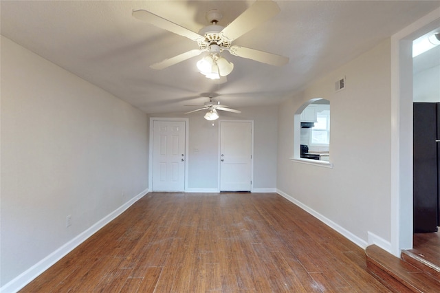 interior space with wood finished floors, visible vents, baseboards, arched walkways, and ceiling fan