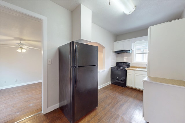 kitchen with black appliances, dark wood-style flooring, under cabinet range hood, and a sink