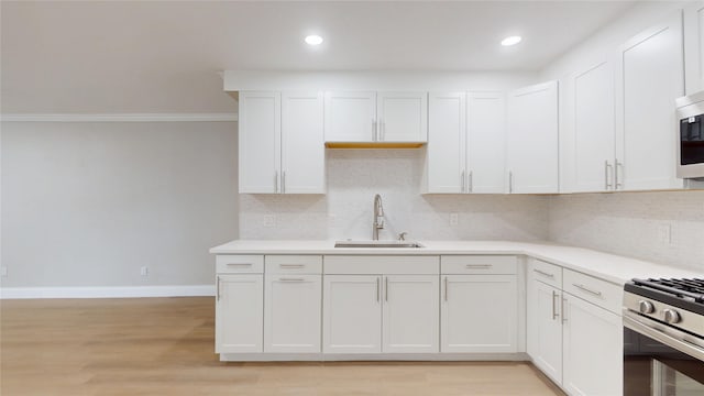 kitchen featuring a sink, white cabinetry, light countertops, and gas stove