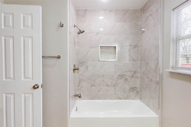 bathroom with shower / bathing tub combination, plenty of natural light, and a textured wall