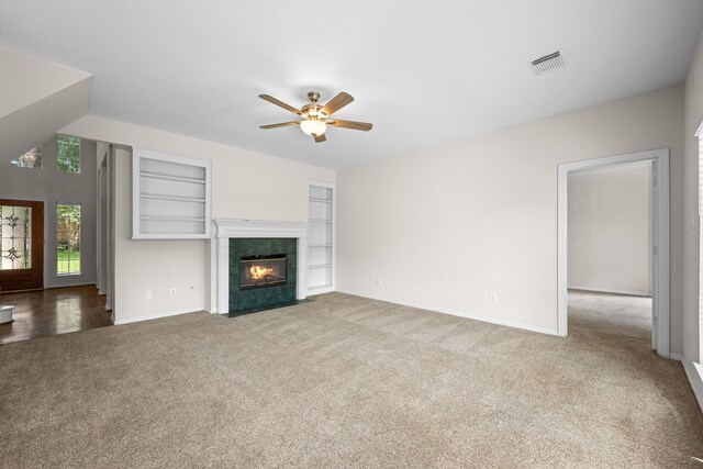 6923 Queensclub Dr, Houston, TX 77069 - unfurnished living room featuring carpet floors, a ceiling fan, built in shelves, and a tile fireplace