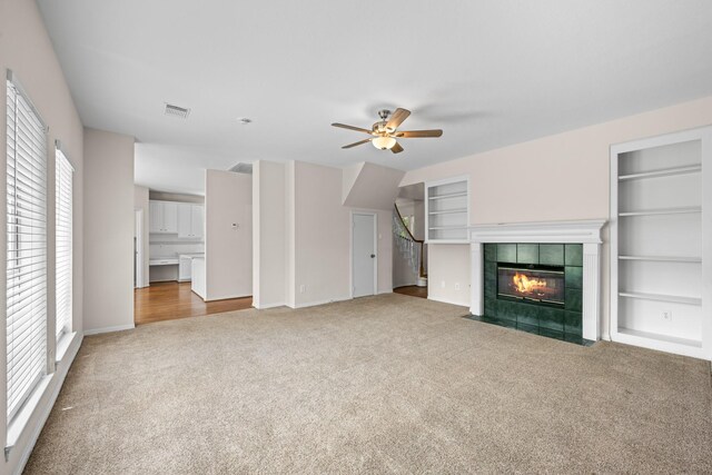 6923 Queensclub Dr, Houston, TX 77069 - unfurnished living room with carpet, ceiling fan, built in features, and a tiled fireplace