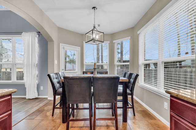 dining area featuring arched walkways, a healthy amount of sunlight, and baseboards