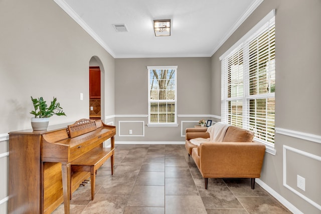 living area featuring baseboards, visible vents, arched walkways, and ornamental molding