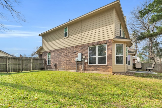 back of house with a patio, a yard, a fenced backyard, and brick siding