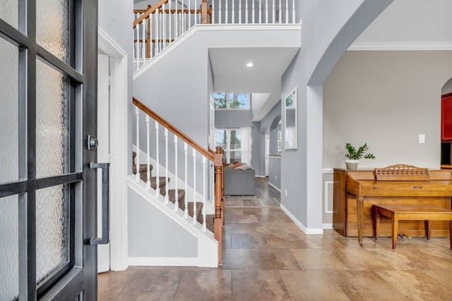 foyer with stairway, arched walkways, and a high ceiling