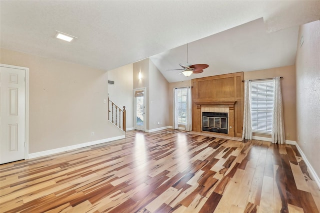 unfurnished living room featuring light wood-style floors, a fireplace, stairway, and vaulted ceiling