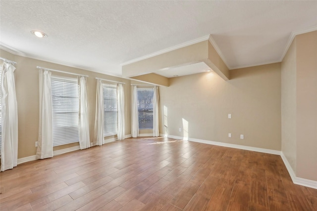 empty room featuring crown molding, a textured ceiling, baseboards, and wood finished floors