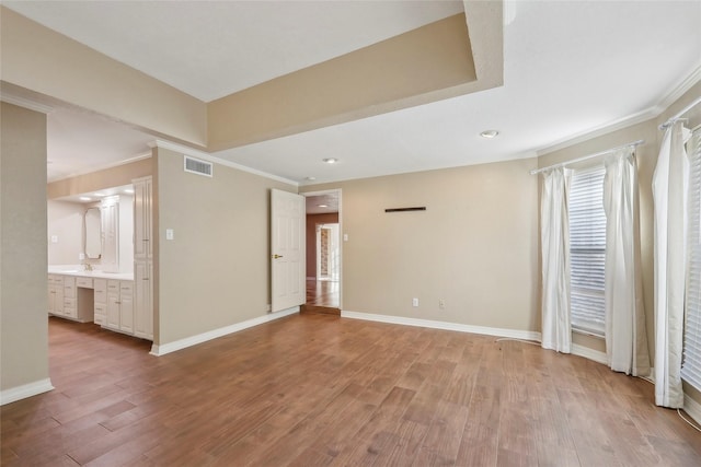 interior space with baseboards, visible vents, ornamental molding, wood finished floors, and a sink