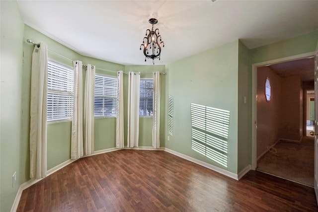 unfurnished room featuring a chandelier, wood finished floors, and baseboards