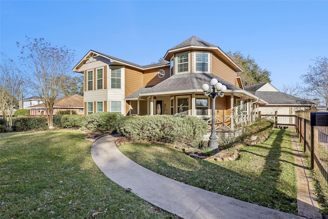 victorian house featuring fence and a front lawn