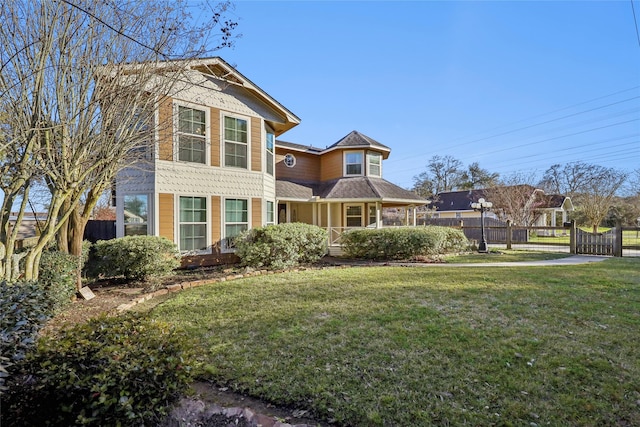 victorian house featuring a front lawn and fence