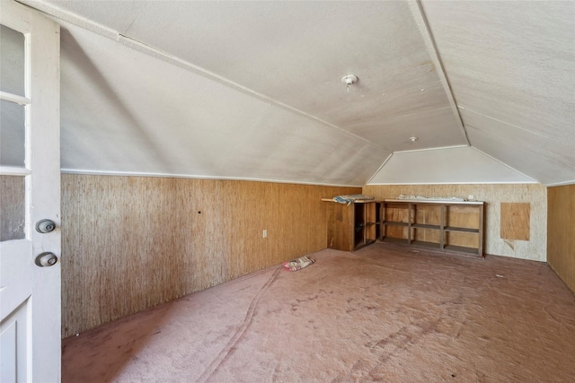 bonus room featuring carpet floors, vaulted ceiling, and wooden walls