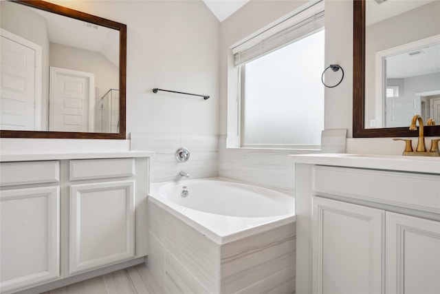 bathroom with a stall shower, a bath, and vanity