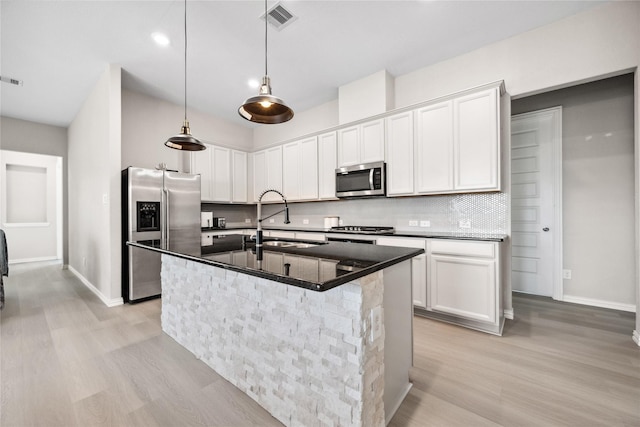 kitchen with visible vents, light wood-style flooring, appliances with stainless steel finishes, a sink, and backsplash