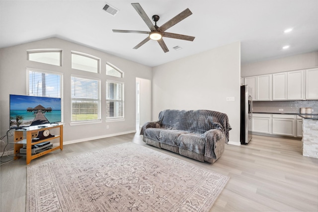 living area featuring lofted ceiling, ceiling fan, visible vents, and light wood-style floors