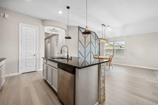 kitchen with arched walkways, a kitchen island with sink, a sink, light wood-type flooring, and dishwasher