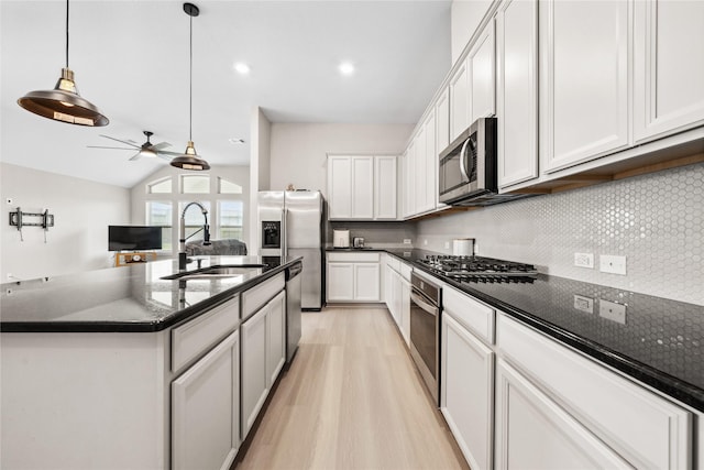 kitchen with tasteful backsplash, lofted ceiling, appliances with stainless steel finishes, light wood-type flooring, and a sink