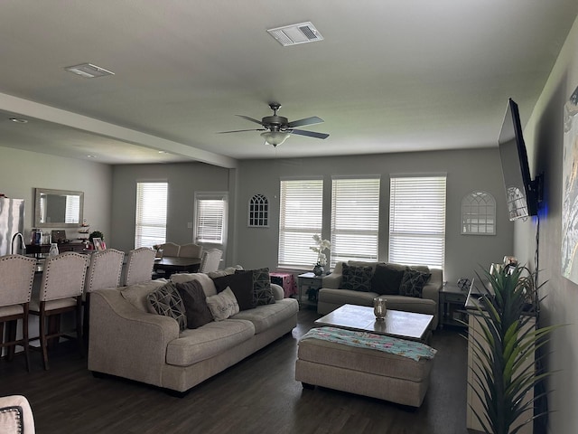 living room featuring dark wood-style flooring, visible vents, and a ceiling fan