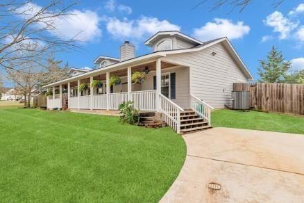 view of front of house featuring central AC unit, a chimney, covered porch, fence, and a front lawn