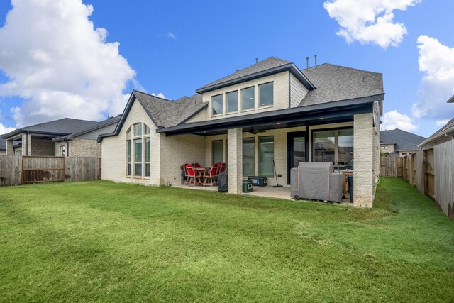 back of house featuring a fenced backyard, roof with shingles, a yard, a patio area, and brick siding