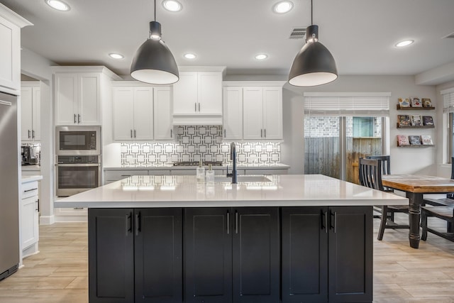 kitchen with light countertops, appliances with stainless steel finishes, and white cabinetry