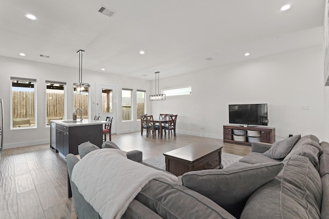 living room featuring light wood-style floors, recessed lighting, visible vents, and baseboards