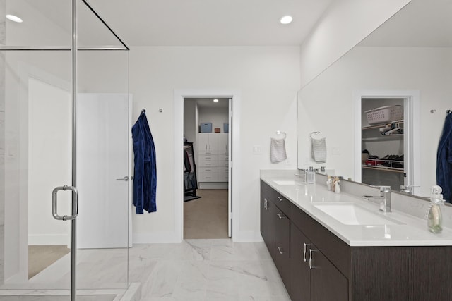 full bath with marble finish floor, a walk in closet, and a sink