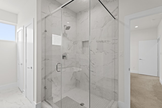 bathroom featuring marble finish floor, a marble finish shower, and baseboards