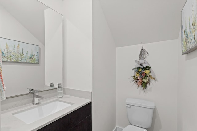 half bathroom featuring vaulted ceiling, vanity, and toilet