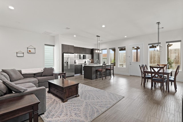 living area with a healthy amount of sunlight, light wood-style floors, baseboards, and recessed lighting