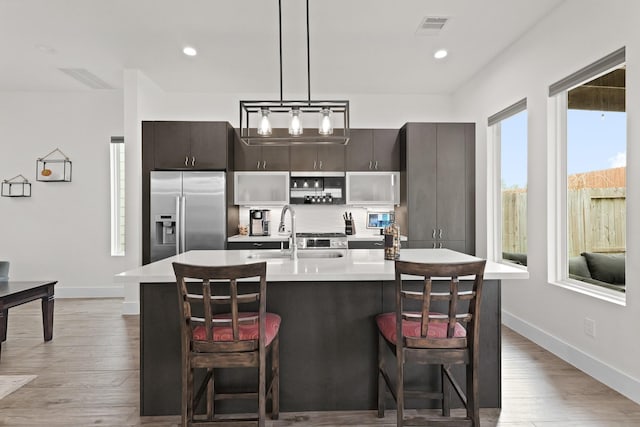 kitchen with stainless steel fridge, visible vents, light countertops, and a sink