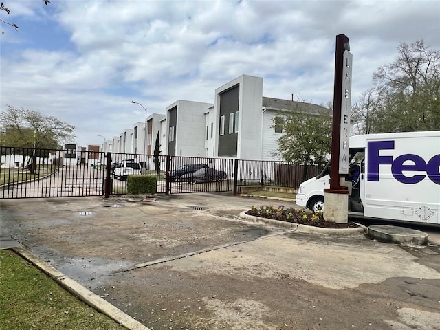 view of street with curbs, street lighting, a gated entry, and a gate