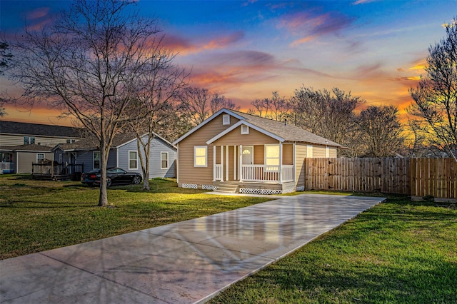 view of front of home with covered porch, fence, and a front lawn