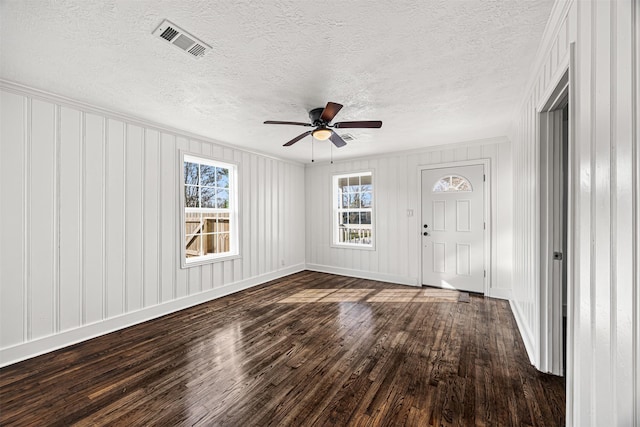 interior space with dark wood-style floors, a wealth of natural light, visible vents, and baseboards