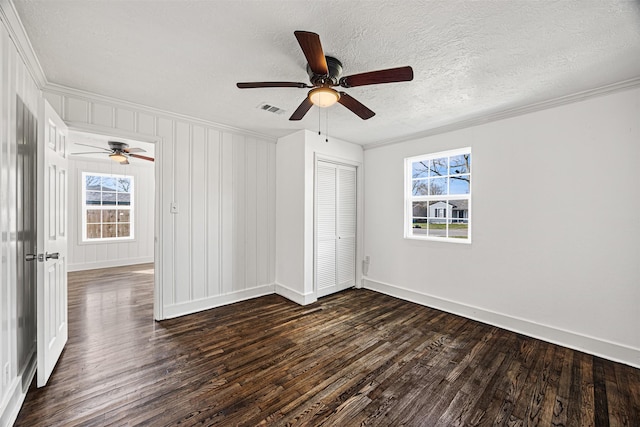 unfurnished bedroom with visible vents, ornamental molding, and dark wood finished floors